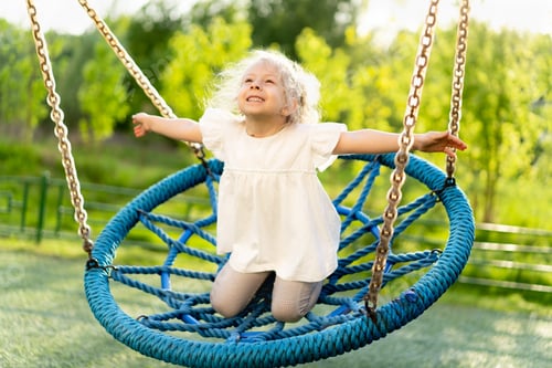 Preview: Little happy girl, swings on a big hammock swing, smiles and rejoices at summer