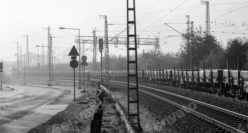 Preview: Grayscale beautiful shot of train goods on a railway track with industrial poles with a misty sky