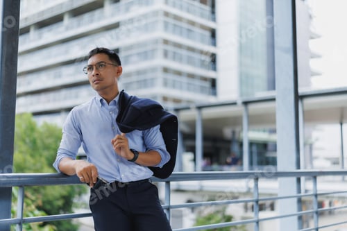 Preview: Pensive businessman leaning on railing outside office building