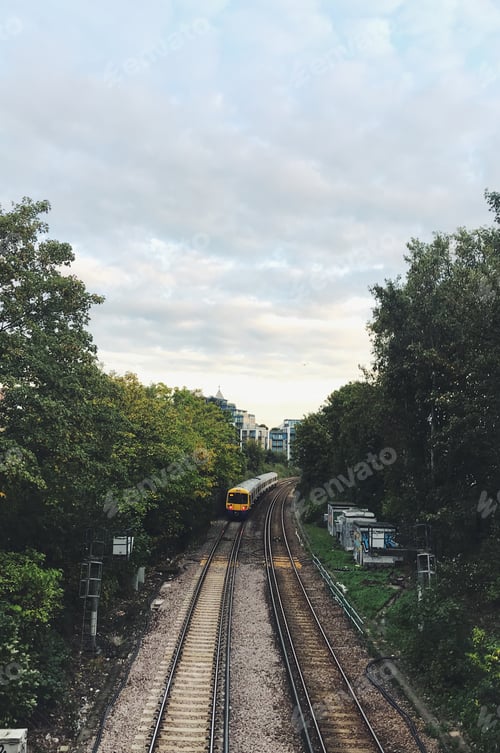 Preview: Train on the track in a europe city. Woods of UK at day light.