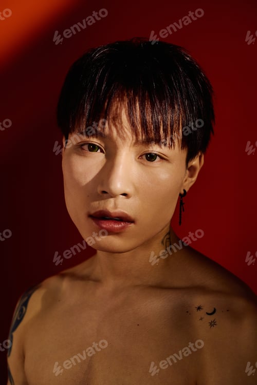 Preview: Stylish young man poses confidently against a vibrant red backdrop showcasing modern aesthetics