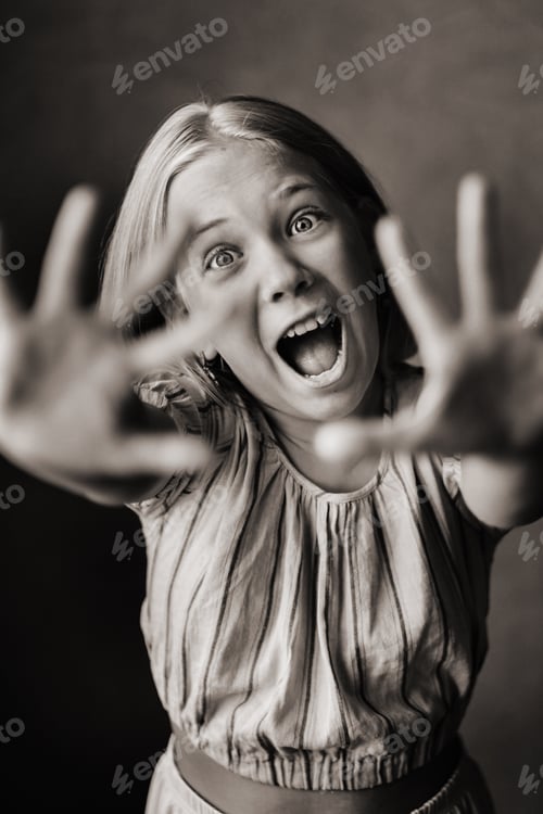 Preview: A happy child, a little girl in a gray T-shirt on a beige background. black and white photo
