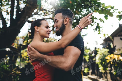 Preview: Happy couple embracing in park with crossed arms