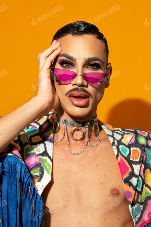 Preview: Portrait of a young drag queen in colorful dress on yellow background