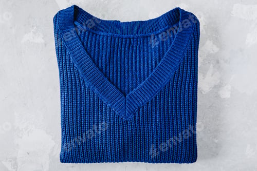 Preview: Sweater. Blue folded sweater on gray stone background.
