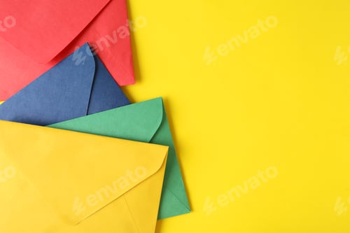Preview: Colorful paper envelopes on yellow background, top view. Space for text
