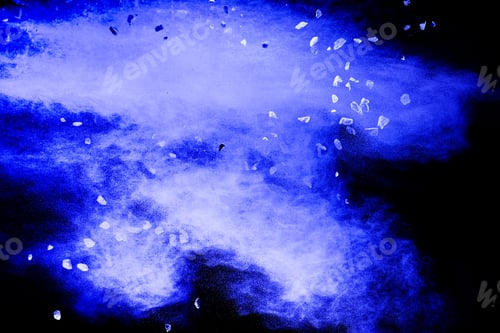 Preview: Split debris of stone exploding with blue powder against black background.