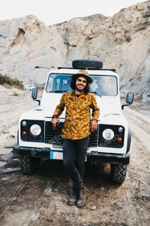 Preview: Stylish man leaning on car hood in canyon