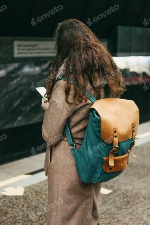 Preview: Young woman using mobile on train subway platform