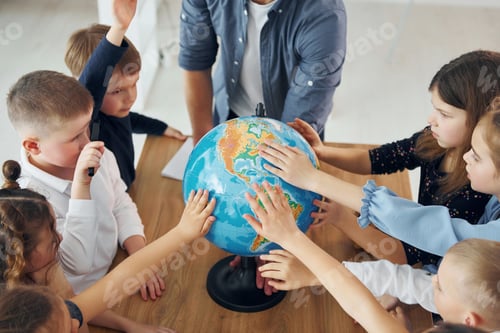 Preview: Touching the Earth globe. Group of children students in class at school with teacher