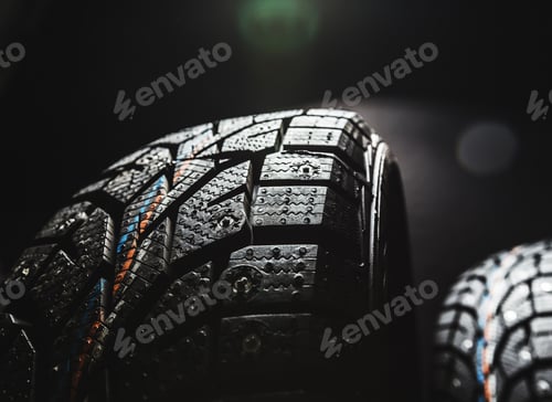 Preview: Close-up view of new tires emphasizing tread design in a dimly lit setting