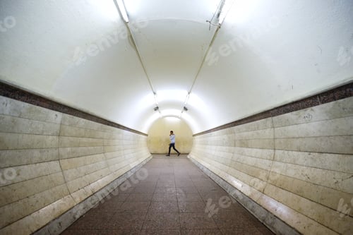 Preview: An adult man walking through a circular subway tunnel.