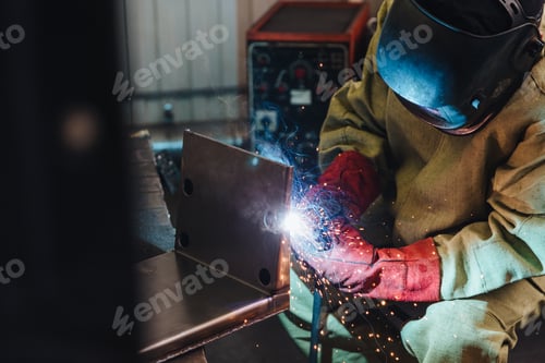 Preview: ndustrial worker or welder wears protective mask and gloves erects technical steel on factory.