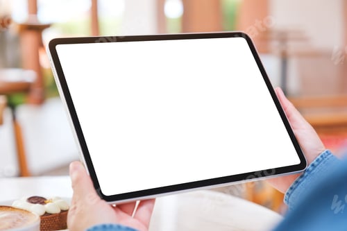 Preview: A woman holding digital tablet with blank white desktop screen with cake and coffee cup