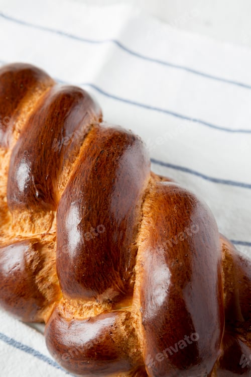 Preview: Homemade jewish challah bread on cloth, side view. Close-up.