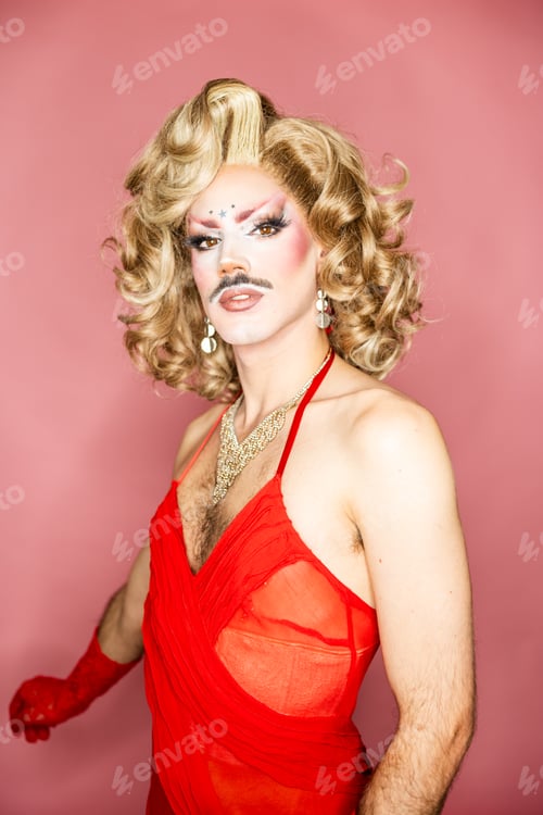 Preview: Blonde Drag Queen With Glamorous Makeup Poses Under a Ring Light in Vibrant Red Attire