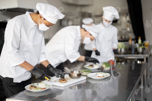 Preview: al group of cooks finishing main courses while working together in the kitchen