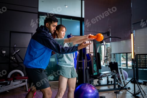Preview: Asian man and woman working out, one is a trainer, the other is an exerciser