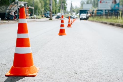 Preview: Traffic safety cones on asphalt of road. Selective focus on striped orange-white warning signs