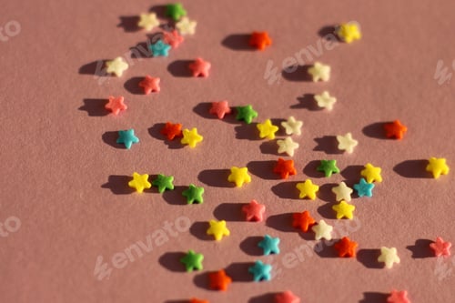 Preview: festive pink background with scattered small multicolored stars. confectionery sprinkles
