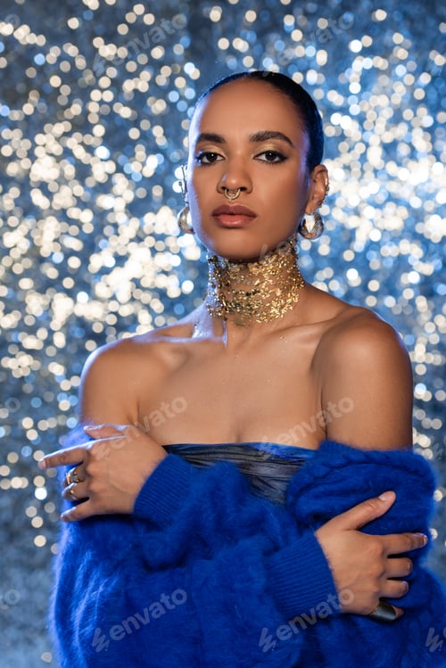 Preview: Fashionable african american woman with golden foil on neck looking at camera on sparkling