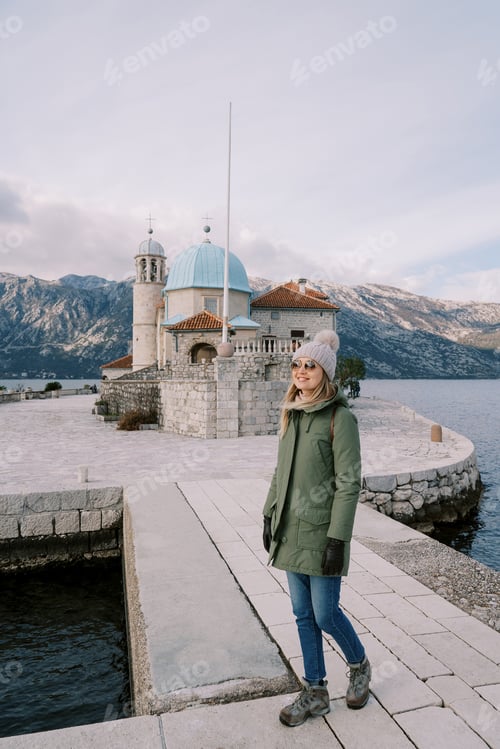 Preview: Smiling young woman stands on the island of Gospa od Skrpjela near the church. Montenegro