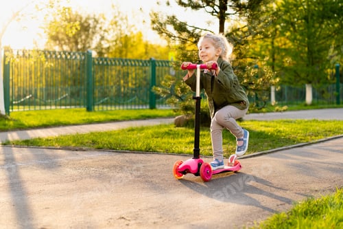 Preview: Little blonde girl on a scooter, happy child