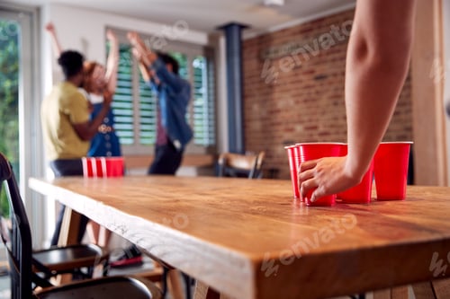 Preview: Multi-Cultural Group Of Friends Playing Game At Home Together Throwing Ball Into Plastic Cup
