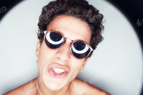 Preview: Say what. Close up portrait of a young man with his lips curled surrounded by a halo of light.