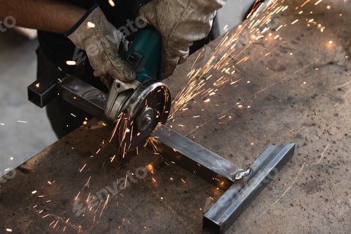 Preview: Male worker using electric grinder in workshop