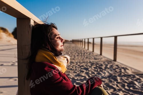 Preview: young woman with eyes closed relaxing at beach at sunset. Holidays and relaxation concept