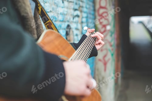 Preview: Musician playing guitar by canal wall, Milan, Italy