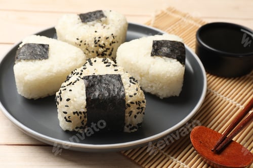 Preview: Rice balls (onigiri), soy sauce and chopsticks on wooden table, closeup. Traditional Japanese dish