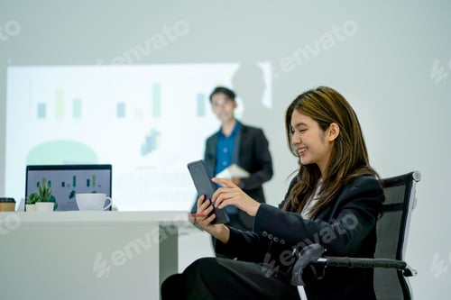 Preview: Pretty Asian business enjoy with tablet during join meeting with business man present in front