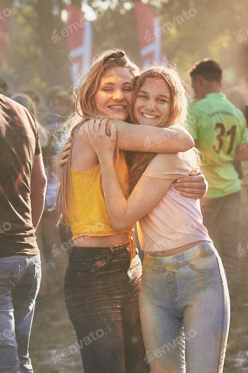 Preview: Portrait of happy smiling young girls with colorful paints on faces and clothes. Two friends