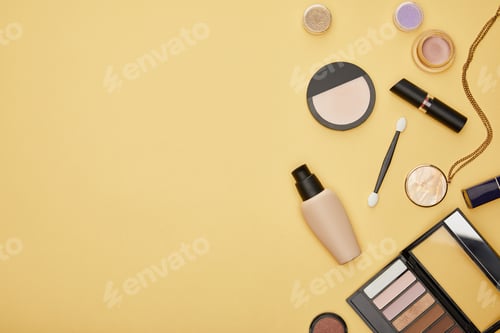 Preview: top view of face foundation and eye shadow isolated on yellow