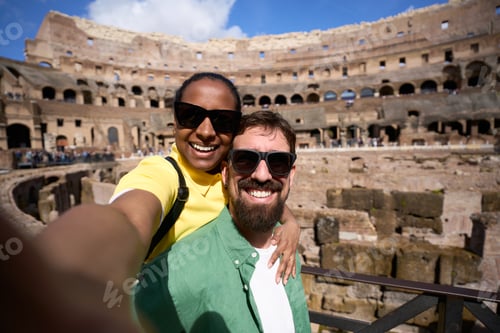 Preview: Happy diverse couple taking selfie at the Colosseum in Rome