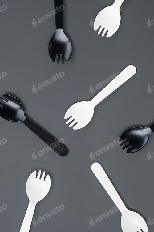 Preview: Black and white plastic forks on gray background. Disposable cutlery and minimalism concepts.