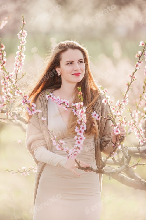 Preview: Delicate portrait of a young millennial woman at sunset in blooming gardens. Allergy to flowers