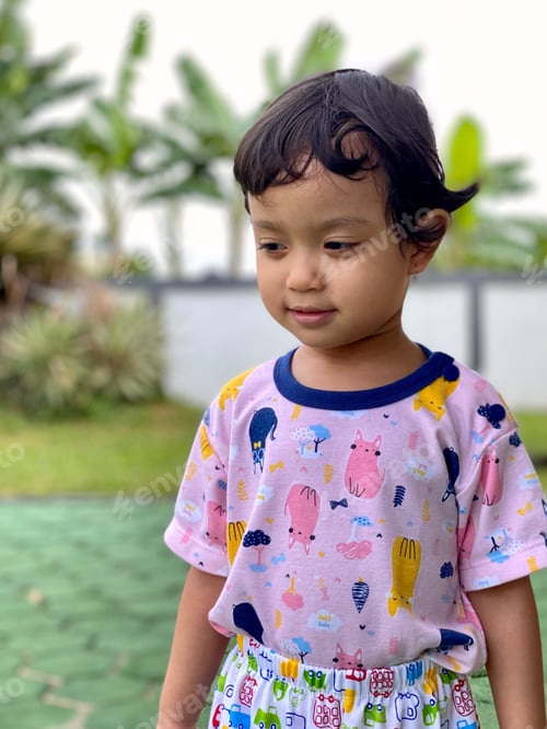 Preview: portrait of a cute and innocent child wearing a purple shirt standing alone