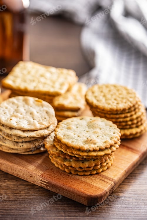 Preview: A stack of crackers neatly arranged on cutting board on wooden tabletop.