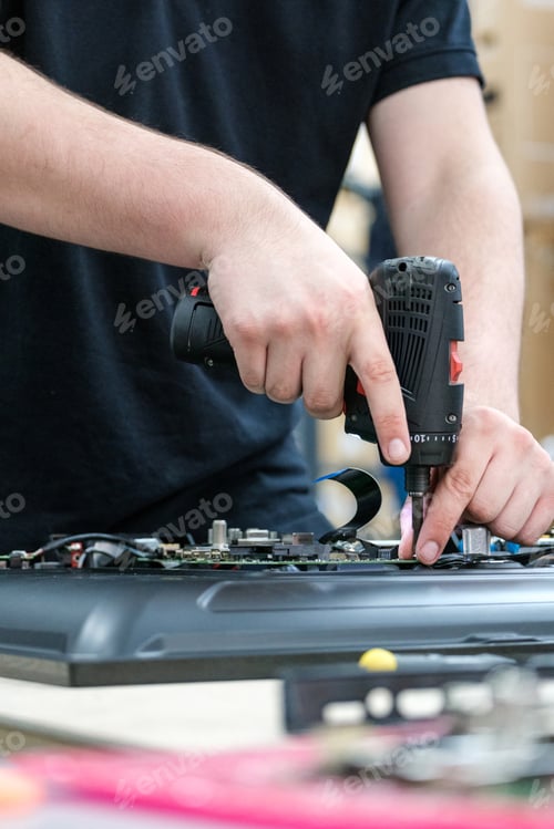Preview: Person repairing TV using a drill and electronic components