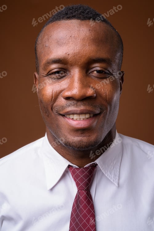 Preview: Studio shot of young African businessman against brown backgroun