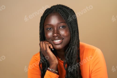 Preview: Young black woman with braids smiling and resting chin on hand