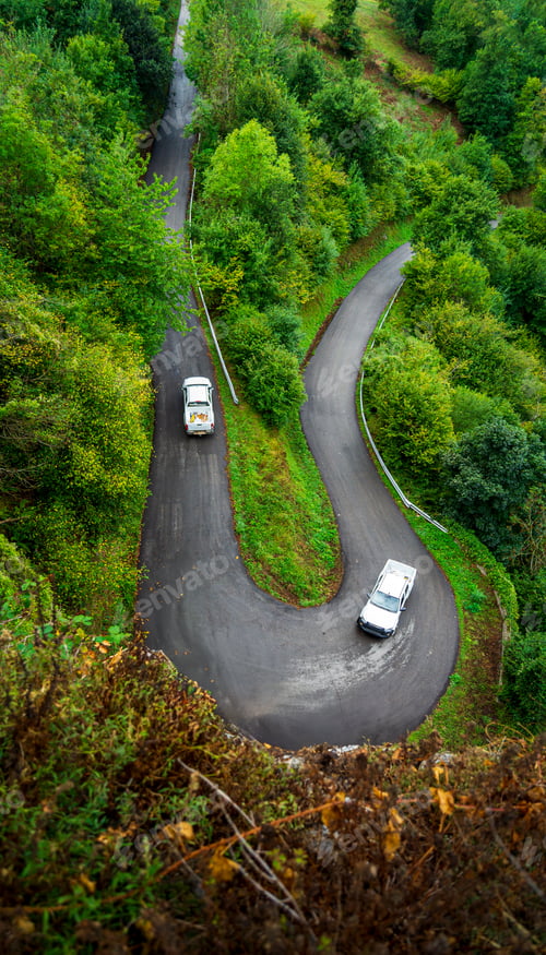 Preview: Scenic mountain road winding through lush Asturias forest on a moody overcast day