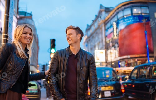 Preview: Young couple on city street at night, London, England, UK