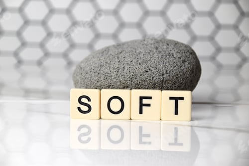Preview: the word soft in front of a grey stone on shiny white marble top