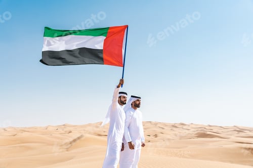 Preview: Two middle-eastern emirati men wearing arab kandura holding emirati flag