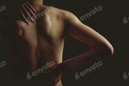 Preview: Nude woman with a back injury on black background