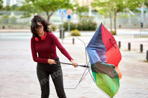 Preview: Woman with a broken umbrella outdoors.
